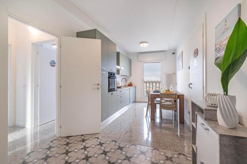 een keuken met witte kasten en een tafel en een eetkamer bij Casa Gabbiano by Ca-sa Check in Chioggia
