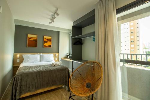 um quarto com uma cama, uma cadeira e uma janela em Studio Novo perto do Allianz Parque em São Paulo