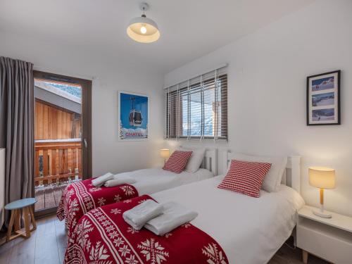 two beds in a room with a window at L'O Rouge - Apt A02 - BO Immobilier- remises sur les forfaits de skis Châtel ou Portes du soleil in Châtel