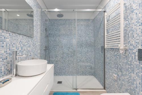 a bathroom with a sink and a shower with blue tiles at Casa da Praia - Matosinhos Mar in Matosinhos