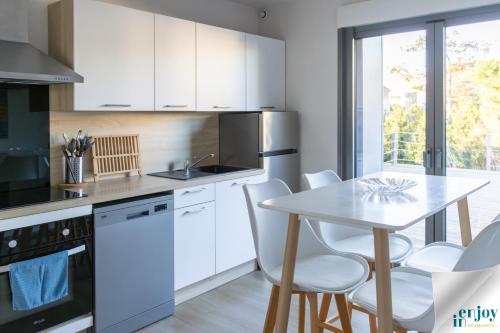 Una cocina con gabinetes blancos y una mesa y sillas. en Villa Jules Petit Gîte, en Agon-Coutainville