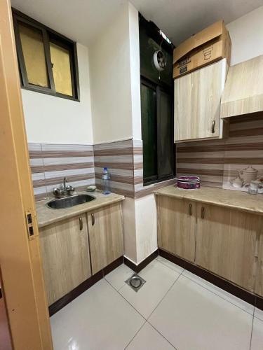 eine Küche mit Spüle und Holzschränken in der Unterkunft Syed Apartment 302 in Islamabad