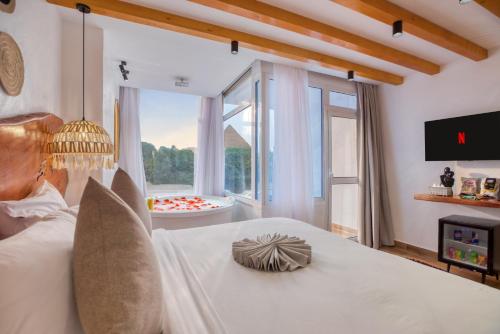 een slaapkamer met een groot wit bed en een groot raam bij Pyramids Vision Hotel in Caïro
