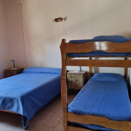 two bunk beds in a room with blue sheets at Las Camelias - chalet zona centro, aerosillas in Villa Carlos Paz