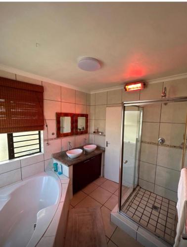 een badkamer met een bad, twee wastafels en een douche bij Holiday Home in Cape Town