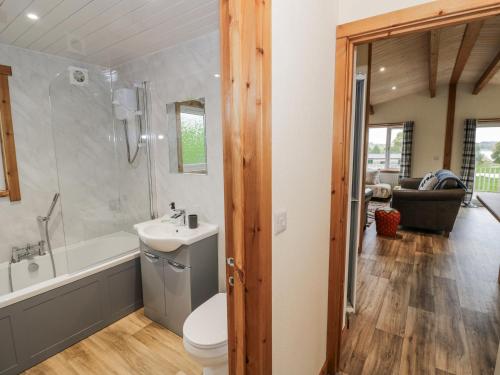 a bathroom with a toilet and a tub and a sink at Willow Lodge in Rugeley