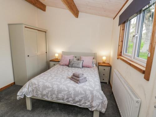 a bedroom with a bed with pink pillows and a window at Willow Lodge in Rugeley