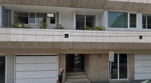 un homme marchant devant un bâtiment avec deux portes de garage dans l'établissement Hostal Auditorio, à Mexico