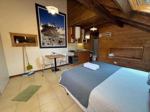 a bedroom with a large blue bed and a table at Campo Base Aparts in El Chalten
