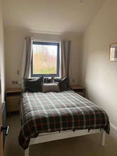 a bedroom with a bed with a plaid blanket and a window at Four Seasons Lodge in Lichfield
