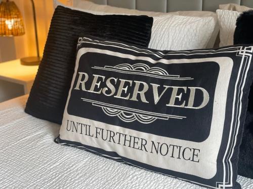 a black and white pillow on a bed with a reserved sign at The Nairn Neuk - Couples Cosy Getaway in Nairn