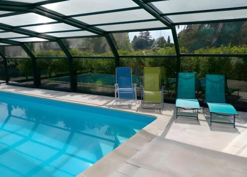 einen Pool mit vier Stühlen und einem Pool in der Unterkunft Gîte Le Campet in Millau