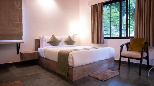 Trisara Boutique Stay في ميسور: غرفة نوم بها سرير وكرسي ونافذة