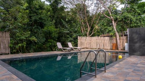 Trisara Boutique Stay في ميسور: مسبح مع كرسيين جلوس بجانب سياج
