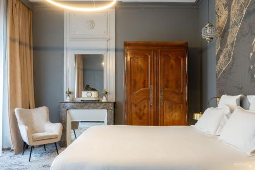une chambre avec un grand lit blanc et une chaise dans l'établissement Le Champlain, à La Rochelle