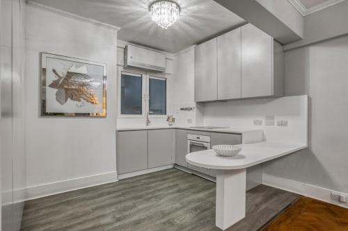 a kitchen with white cabinets and a white table at The Grande Mayfair Apartment in London