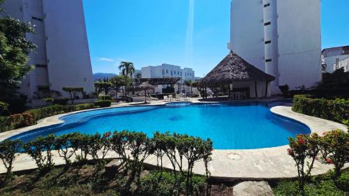a large blue swimming pool with trees in front of buildings at Familiar, amplio y con alberca in Puerto Vallarta