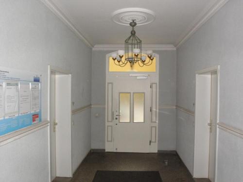 a hallway with a white door and a chandelier at Central Apartments Chemnitz KASSBERG in Chemnitz