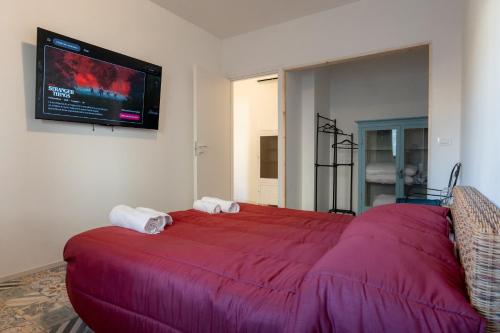 - une chambre avec un grand lit rouge et une télévision à écran plat dans l'établissement FIAMBI & b, à Colugna