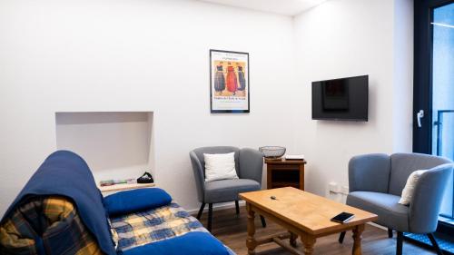 a living room with a couch and chairs and a tv at Appartement 1 chambre proche stations in Saxon