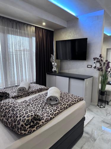 two beds in a bedroom with a flat screen tv at Studio apartman Luna in Vinkovci