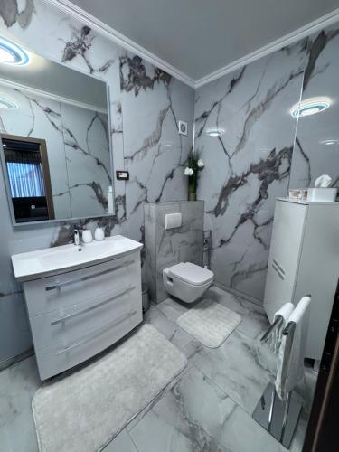 a bathroom with a sink toilet and a mirror at Studio apartman Luna in Vinkovci