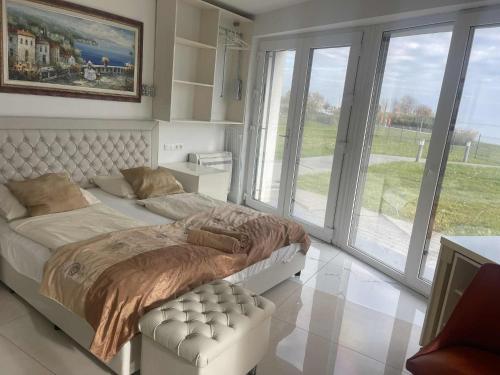 a bedroom with a large bed and large windows at Balatonparti Gyöngyszem in Keszthely