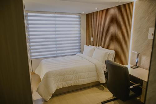 a bedroom with a bed and a desk and a window at Torre U kooliving in Manizales