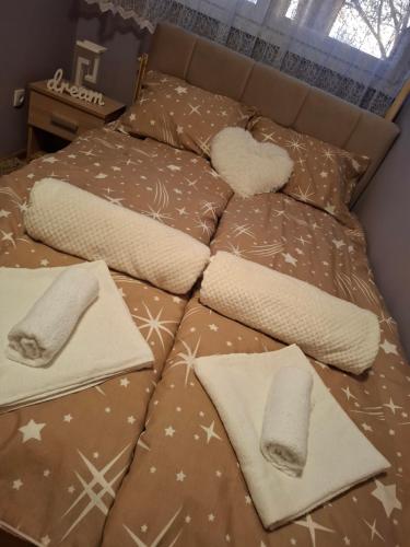 Una cama con mantas y almohadas encima en Stan na dan DN-apartman, en Kula