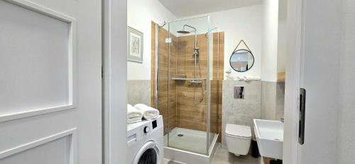 a bathroom with a shower and a washing machine at Apartament Lubię Morze by TriApart in Jantar