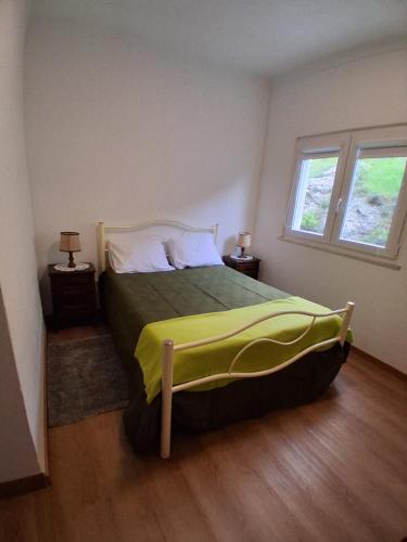 a bedroom with a bed with a yellow blanket on it at Piscinas, Serra da Estrela AL in Bouça