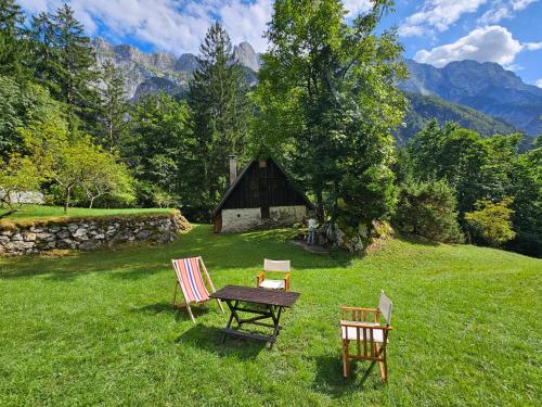 Una mesa y sillas en un campo con un granero. en Hiška Polhec, en Bovec