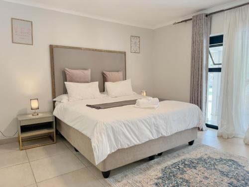 a bedroom with a large bed with white sheets and pink pillows at Berrybliss Guesthouse - Sandton in Sandton