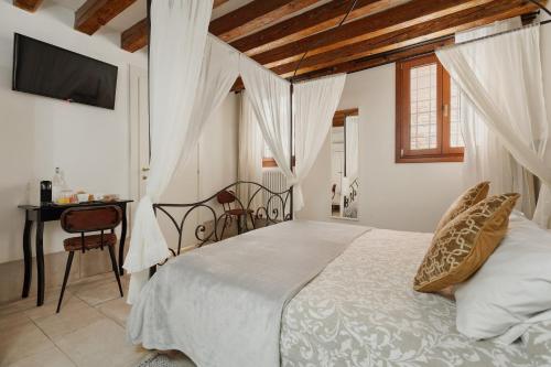 a bedroom with a bed and a desk and a television at Bianca Cappello House in Venice