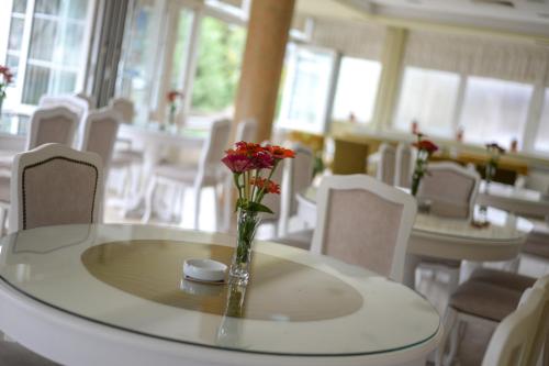 una mesa con un jarrón de flores encima en Hotel Fontana, en Zenica