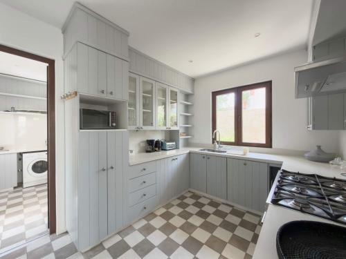 Casapueblo Rent Cachagua CP 34 في Cachagua: مطبخ بخزائن بيضاء وأرضية مربعة