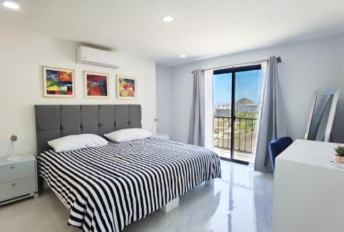 een slaapkamer met een bed en een groot raam bij Morgan Hotel Boutique & Residences, Los Cabos in Cabo San Lucas
