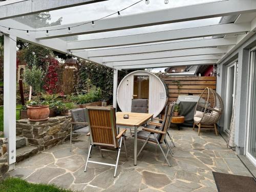 een terras met een houten tafel en stoelen onder een witte pergola bij Haus am Tor zur Eifel in Mechernich