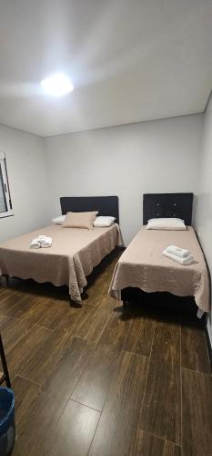 Dos camas en una habitación con suelo de madera. en POUSADA CITRINO, en Ametista do Sul