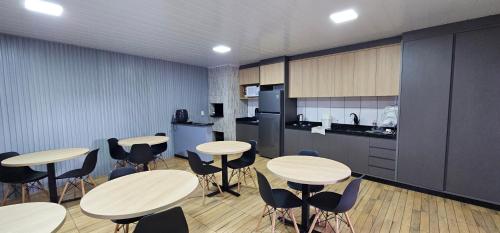 une pièce avec des tables et des chaises et une cuisine dans l'établissement POUSADA CITRINO, à Ametista do Sul