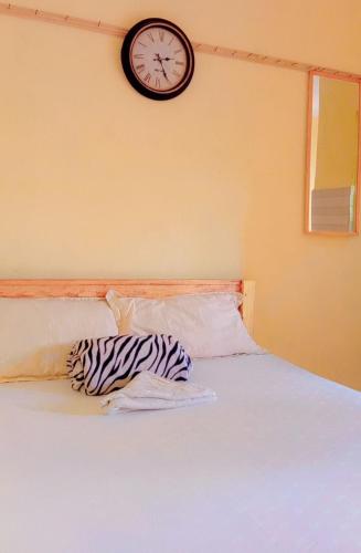 ein Zebrakissen auf einem Bett mit einer Uhr an der Wand in der Unterkunft Swahili BNB Homes in Kilifi
