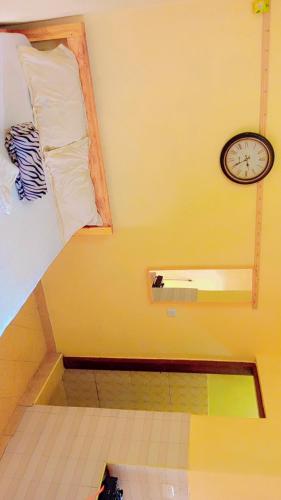 Zimmer mit einem Bett und einer Uhr an der Wand in der Unterkunft Swahili BNB Homes in Kilifi