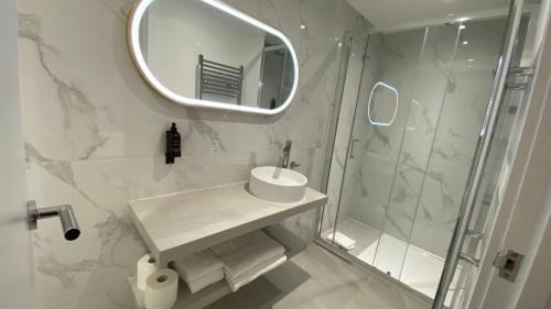 a bathroom with a sink and a shower with a mirror at RIOSHOUSE Henley in Henley on Thames