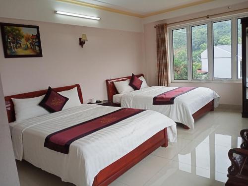 Una habitación de hotel con dos camas y una ventana. en Khách sạn Thành Loan 2, en Cao Bằng