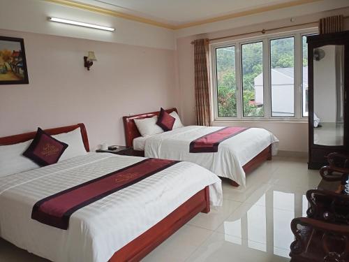 Una habitación de hotel con dos camas y una ventana. en Khách sạn Thành Loan 2, en Cao Bằng