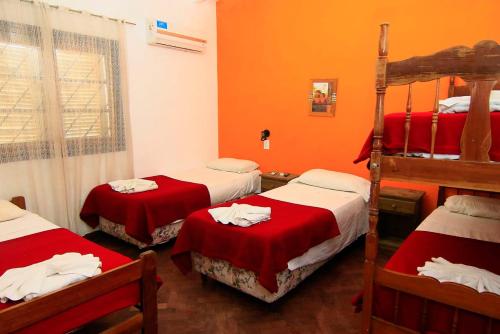 a room with three bunk beds with red sheets at Hotel ALTOS DE ARUNA in Bialet Massé