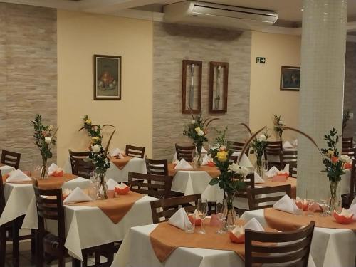 a restaurant with white tables and chairs with flowers at Hotel Vitoria Marchi in Serra Negra