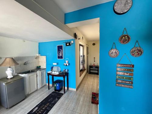 Indigo Orchid Homestay - A spacious, serene villa with terrace and farm view في Saligao: مطبخ ازرق مع طاولة وساعة على الحائط