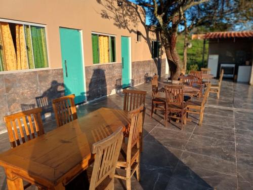 una fila de mesas y sillas de madera en un patio en pousada tucano, en São José da Barra