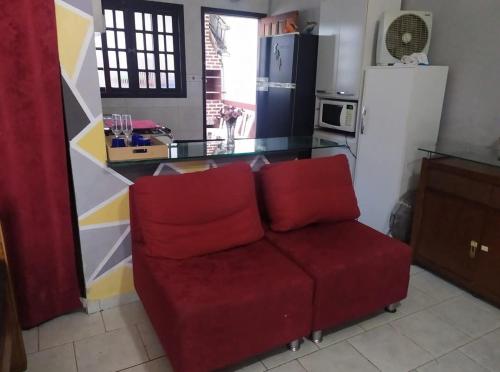 a living room with a red couch in a kitchen at Casa Temporada Caraguatatuba in Caraguatatuba